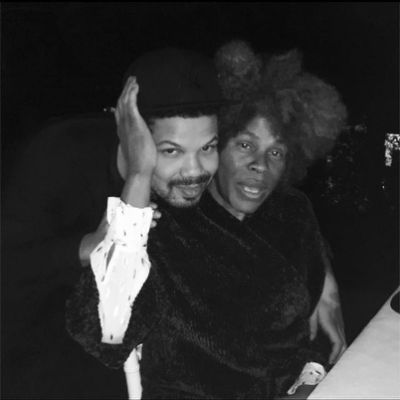 A monochrome picture shows Jake resting his head on Janet's shoulder from behind.